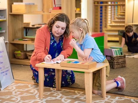 Teacher working with a young student on a project.